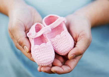 Hands holding pink baby shoes