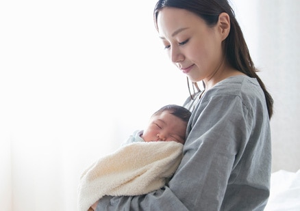 standing woman holding newborn baby