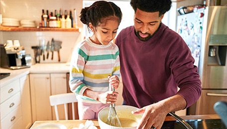 Parent and child preparing food together at home