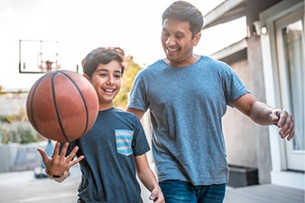 Happy child spinning a basketball while walking with parent