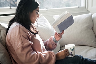 Person reading book on a couch