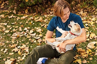 Teen holding dog in a pile of leaves