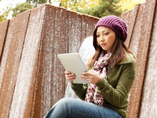 Woman reading tablet outside